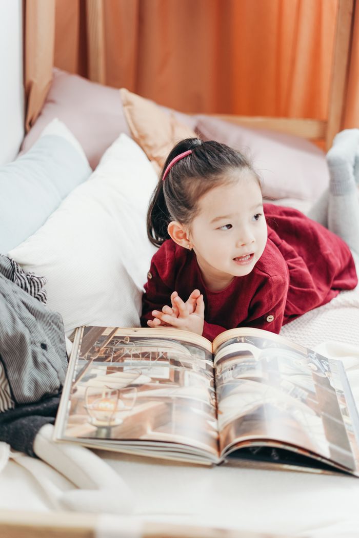 A young child enjoying a book in a comfortable, cozy bedroom environment.