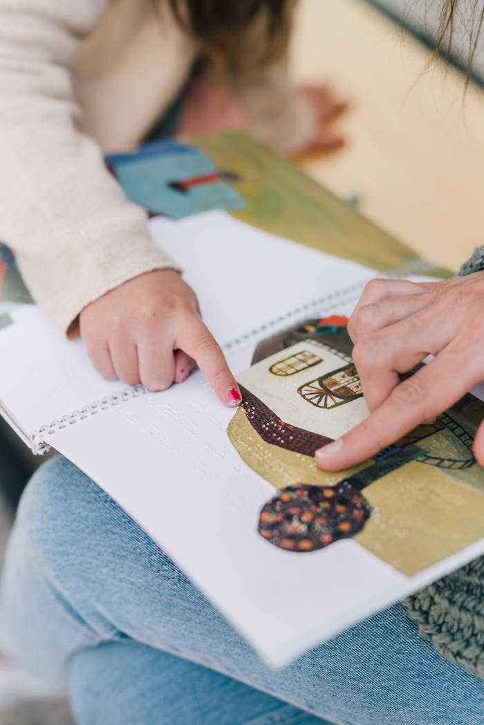 Child and adult hands pointing at illustrations in a book, fostering learning and connection.